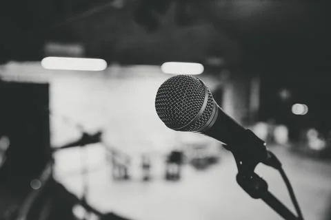 Microphone points across dim stage with monochrome concert lighting Stock Photos