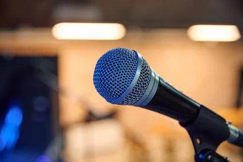 Microphone points toward recording studio under warm amber light Stock Photos