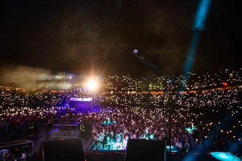 Microphone on stage against crowd with flashlights at night concert Stock Photos