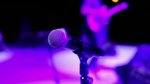 Microphone on stage rock man playing guitar, soft blur neon lights background Stock Footage 308915080