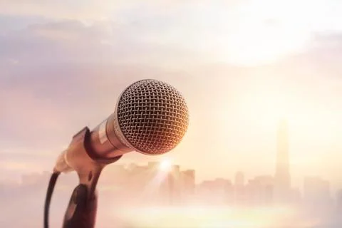 Microphone on stage on warming sunset city background Stock Photos