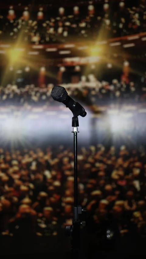 A microphone on a stand with a blurred background of a lively audience and brigh Stock Footage 293466816