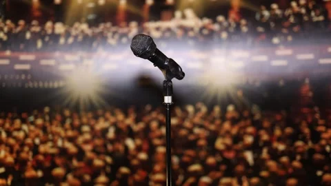 A microphone on a stand set against the backdrop of a vibrant audience and glowi Stock Footage 293469839