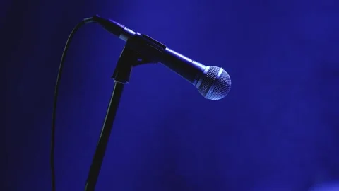 Microphone on stand under blue stage lighting with bokeh background Stock Footage 344162753