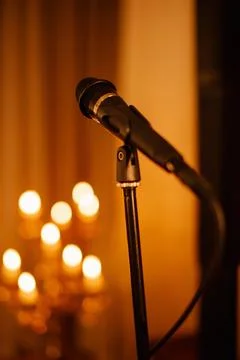 Microphone on stand with warm lighting and blurred candle background  Stock Photos