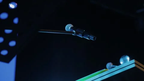 A microphone suspended from a stand, positioned in front of a dark background. Stock Footage 319480064