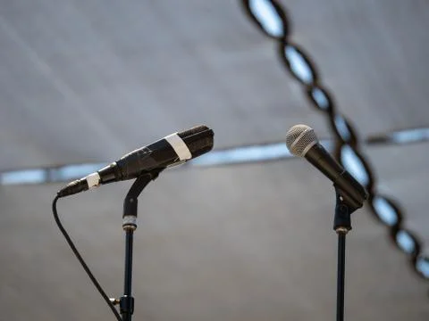 Microphones side by side awaiting a performance on an outdoor stage Stock Photos