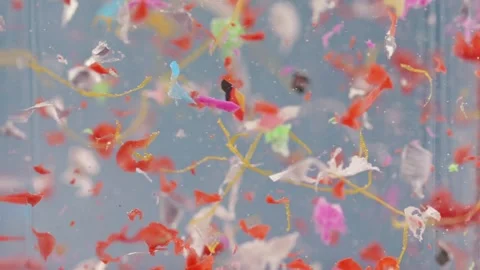 Microplastic fragments float in water, seen in a slow-motion close-up, show.. Vidéo 289843969
