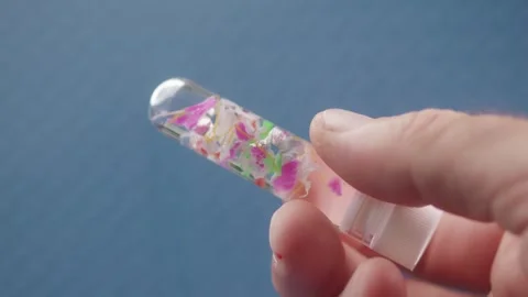 Microplastic fragments in a water sample test tube, showing environmental c.. Vidéo 289843779