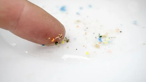 Microplastic particles on a human finger. 스톡 사진