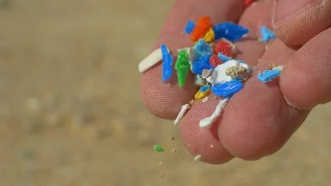 Microplastics in hands close up. Small plastic pieces falling on sand slow Stock Footage 224123902