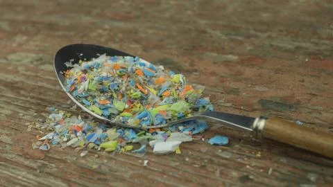 Microplastics in a spoon. A concept of consuming micro plastic particles. Stock Photos