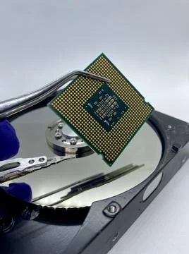 Microprocessor CPU chip on pincer against a silver hard disk plate closeup vi 스톡 사진