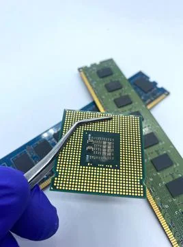 Microprocessor CPU kept on a pincer against memory RAM closeup view 写真素材