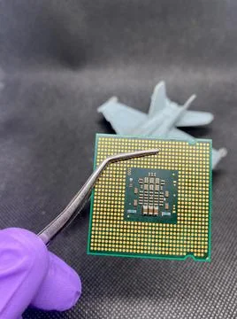 Microprocessor CPU on a pincer and glove hand against an fight plane closeup  Stockfoto's