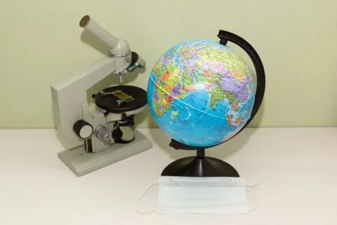 Microscope and globe with a protective mask Stock Photos