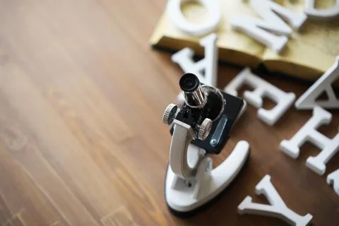 Microscope and Scattered Alphabet Letters on Wooden Surface Stock Photos