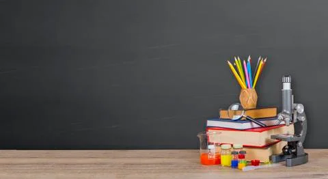 Microscope book and test tubes in front of chalkboard. Stock Photos