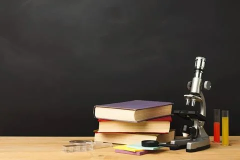 Microscope with books and test tubes on wooden table Stock-Fotos
