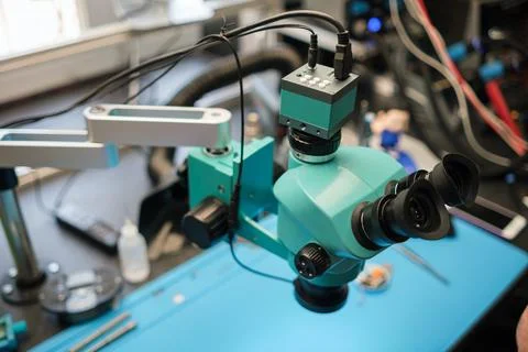 Microscope with dual eyepieces and adjustable arm positioned on a blue work Stock Photos