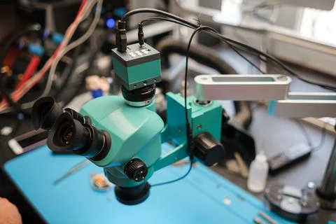 Microscope with dual eyepieces and adjustable arm positioned on a blue work Stock Photos