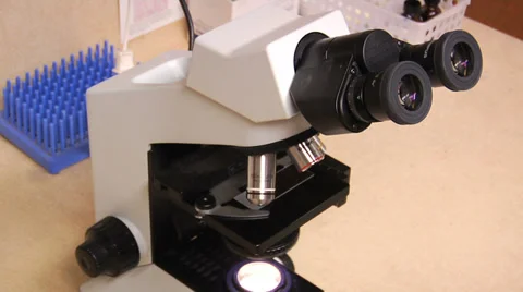 A microscope is featured on a table in a lab. Vídeo Stock 34489834