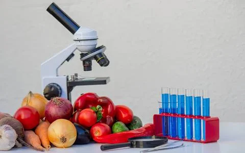 Microscope with fresh vegetables and test tubes Stock Photos
