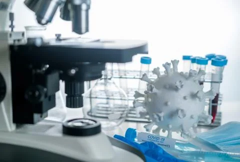 Microscope in laboratory with model of coronavirus and test vials Foto stock