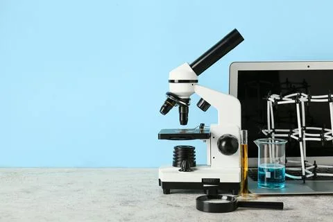 Microscope with laptop, molecular model and flasks of samples on blue backgro Stock Photos
