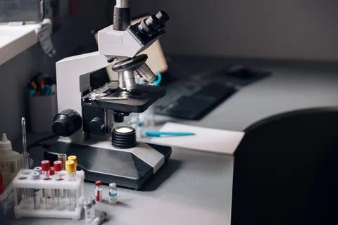 Microscope, rack with test tubes and vials on table in laboratory Foto stock