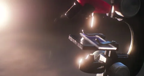 The microscope rotating on a dark background in the light of a mysterious glow 库存影片 151736589