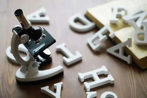 Microscope with Scattered Letters and Open Book on Wooden Table Stock Photos