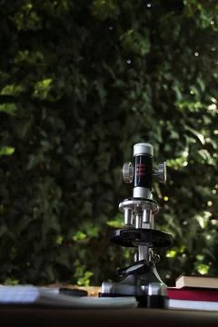 Microscope standing on a table against a green background. Stock Photos
