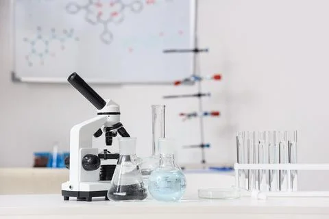 Microscope with test tubes and flasks of water samples on table in research l Фото