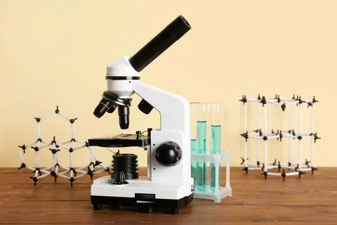 Microscope with test tubes of samples and molecular models on wooden table ag Photos