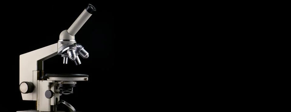A microscope with three lenses on a black background. Stock Photos