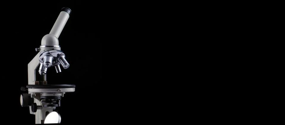A microscope with three lenses on a black background. Stock Photos
