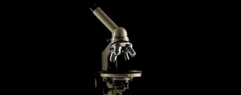 A microscope with three lenses on a black background. Stock Photos