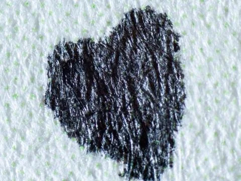 Microscopic macro photograph of tiny black colored heart drawn on paper 库存照片