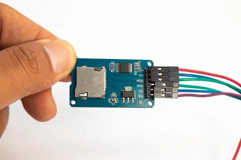 A microSD card reader module with its connecting cable is held in the hand. T Stock Photos