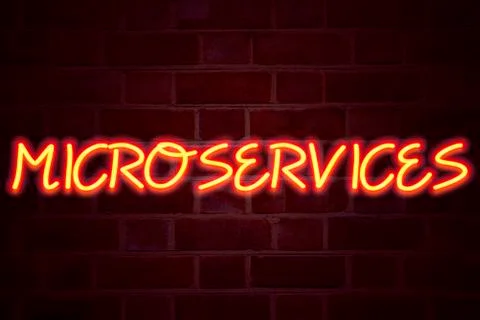 Microservices neon sign on brick wall background. Fluorescent Neon tube Sign  Stock Photos