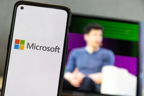 Microsoft logo and Sam Altman in background on screen.Microsoft hires Sam Altman Stock Photos