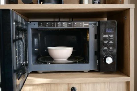 Microwave with a bowl inside on a kitchen shelf Stock Photos
