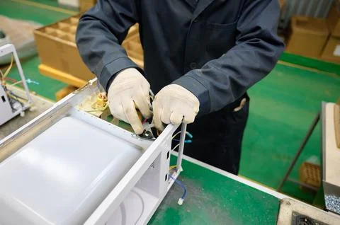 Microwave oven assembly process in a factory with skilled worker using tools and Stock Photos