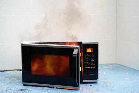 Microwave oven on fire. the concept of fire in the kitchen. Stock Photos