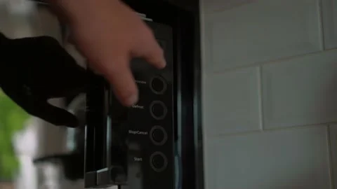 Microwave timer set for two minutes thirty seconds by male hand count down Stock Footage 130319871