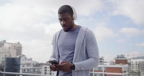 Mid-30s man tapping phone, starting music listening and dancing on rooftop Stock Footage 337943906
