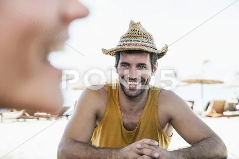 Mid Adult Couple Sitting At Beach, Smiling