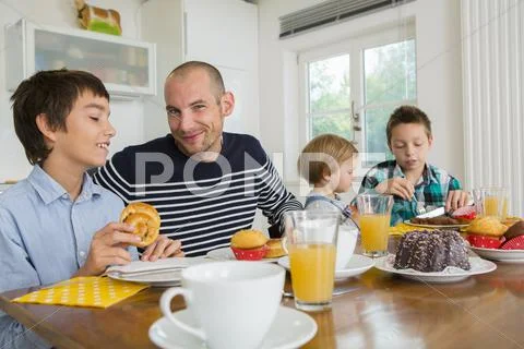 Mid Adult Man And Family Having Tea At Kitchen Table
