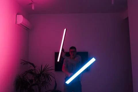 Mid adult man funny with led neon laser at home, samurai or Jedi Stock Photos